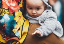 17 Tips for Traveling with a Newborn An image of a woman carrying a baby