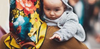 17 Tips for Traveling with a Newborn An image of a woman carrying a baby